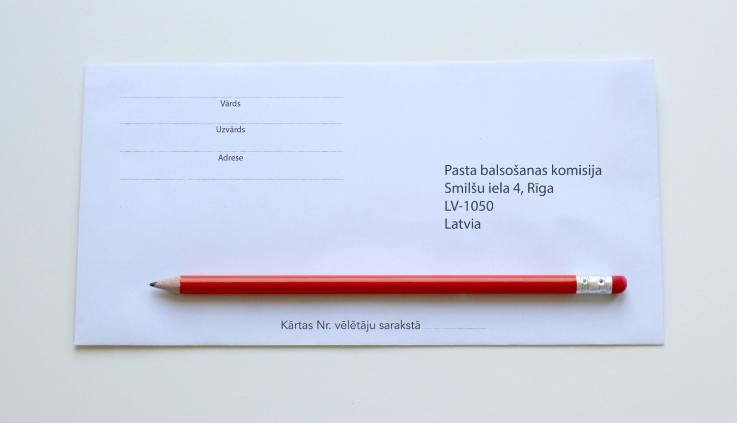 Balta aplokne uz galda ar sarkanu zīmuli